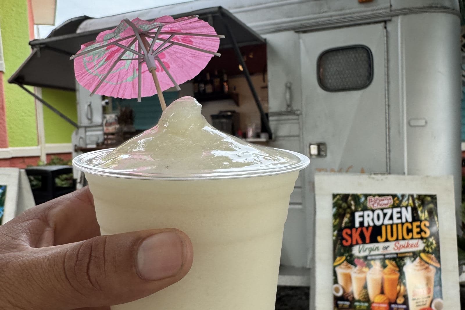 A frozen daiquiri with a paper umbrella, held at the truck window