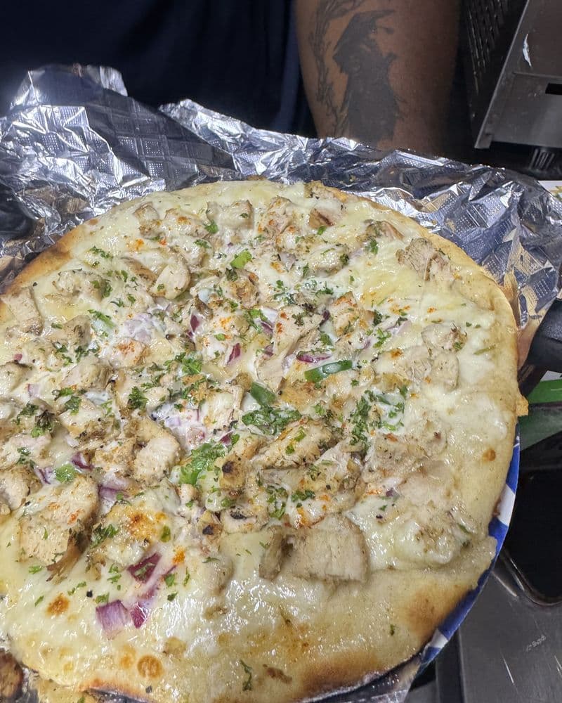 A whole flatbread under melted cheese and herbs