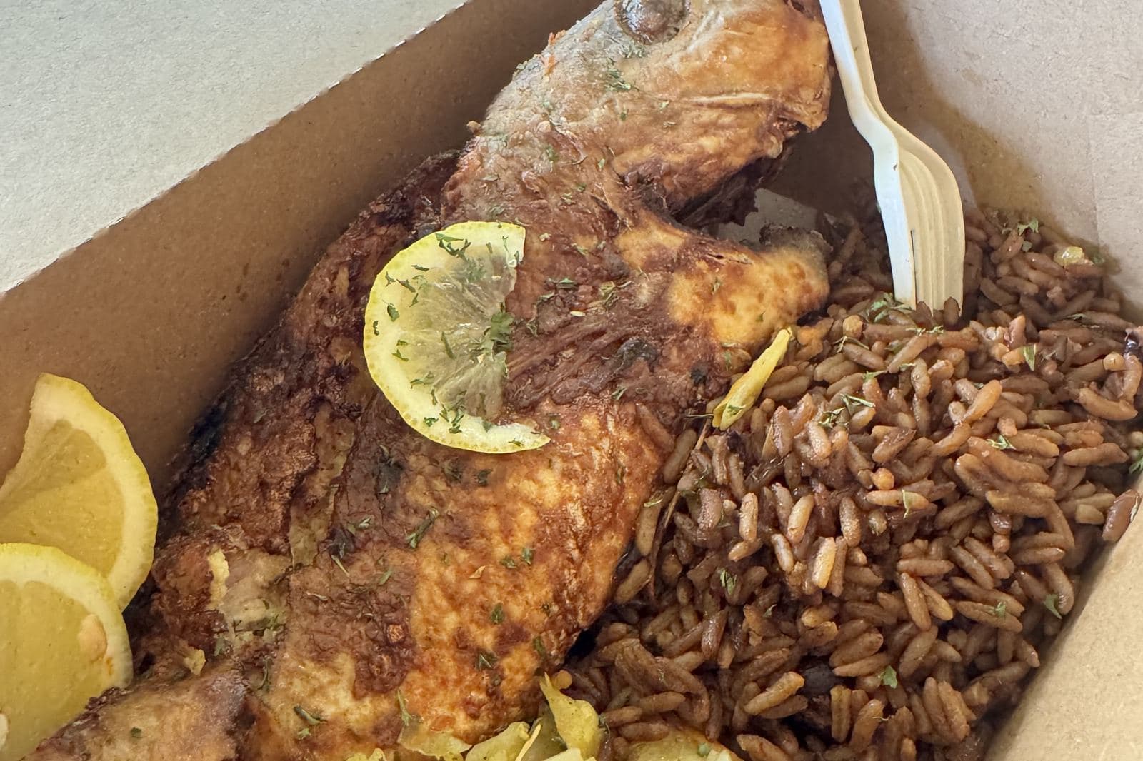 A whole fried fish with peas n' rice and lemon