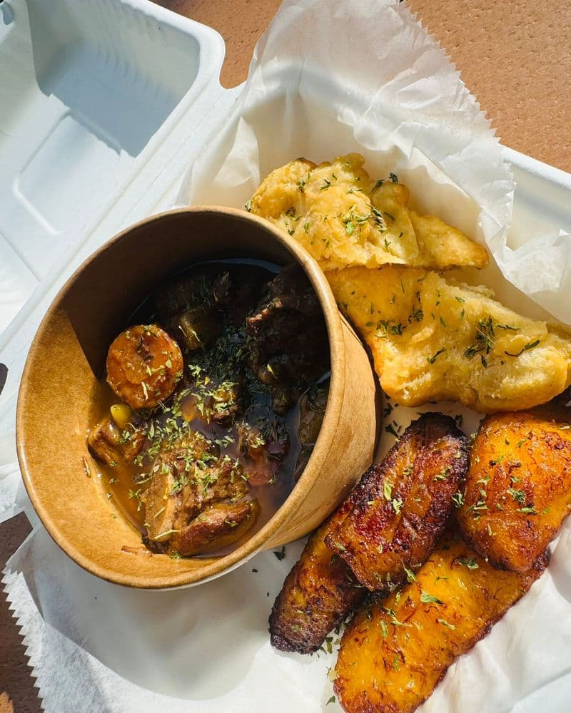 A bowl of stew beside fried plantain and dough